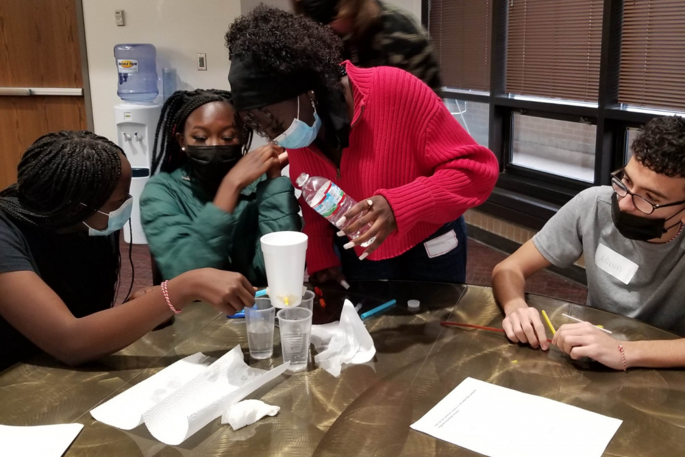 Students testing a variable rate irrigation system crafted from foam cup and straws